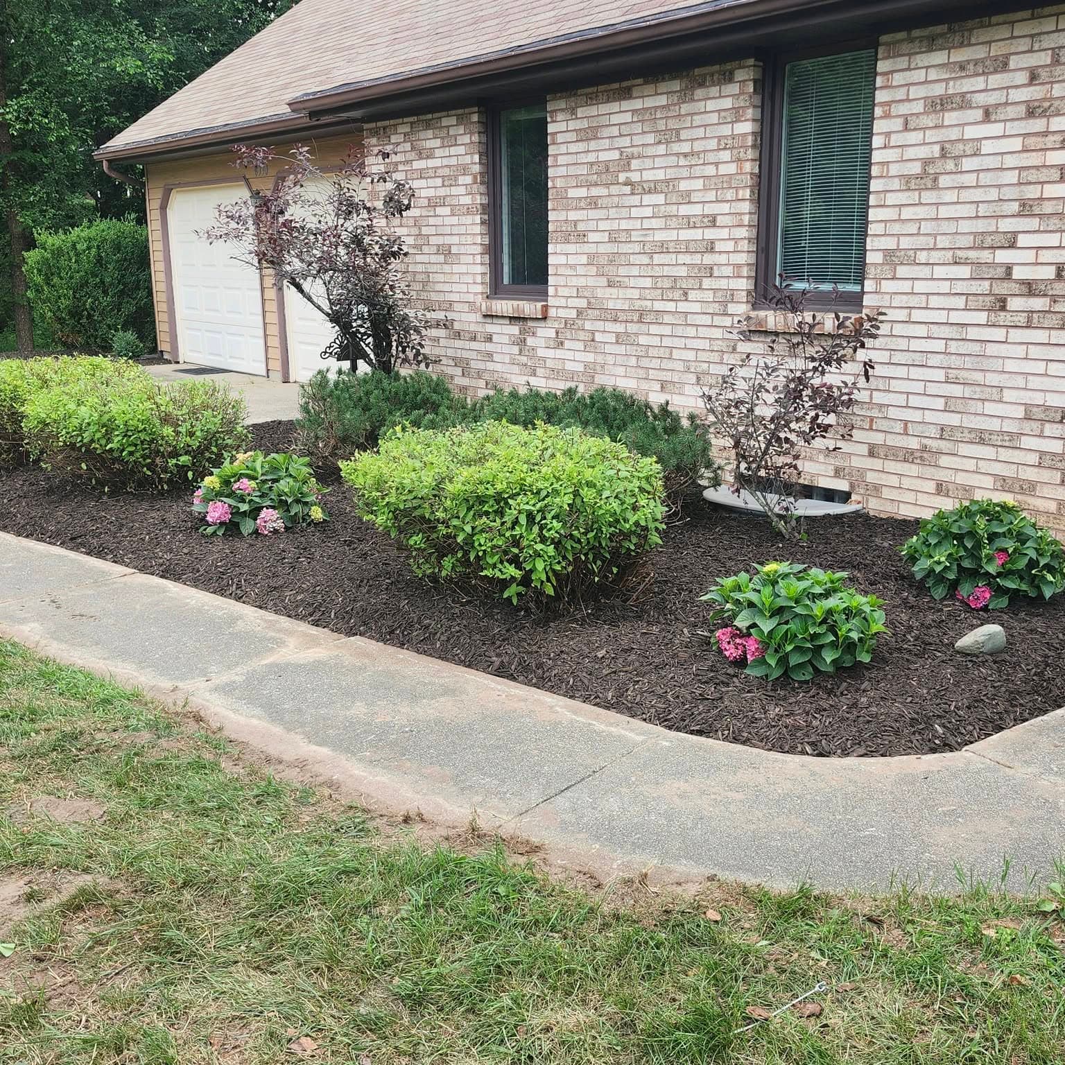 Finished front-yard beds with fresh mulch, shrubs, and flowers in Greater Grand Rapids